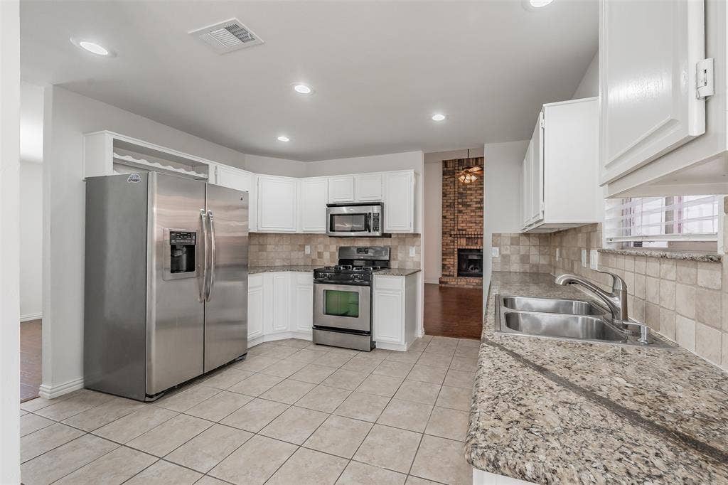 617 Dover Court, Coppell, TX 75019 Kitchen featuring tile flooring, white cabinetry, stainless steel appliances, granite countertops, and a tile backsplash