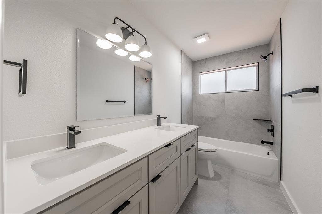 617 Dover Court, Coppell, TX 75019 Second floor full bathroom has dual vanity with integrated sinks and black-finish faucets, and tiled bathtub/shower combo