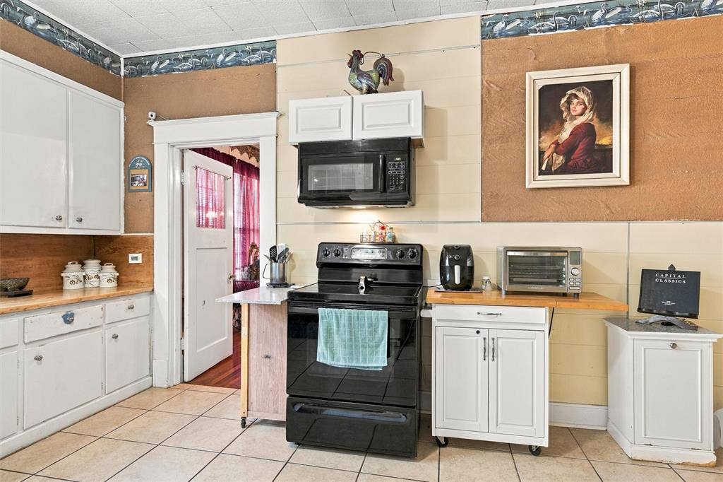 2725 Morrow Avenue, Waco, TX 76707 Kitchen with white cabinetry, tile flooring, a built-in microwave, a black range, and a doorway with a glass-paned door
