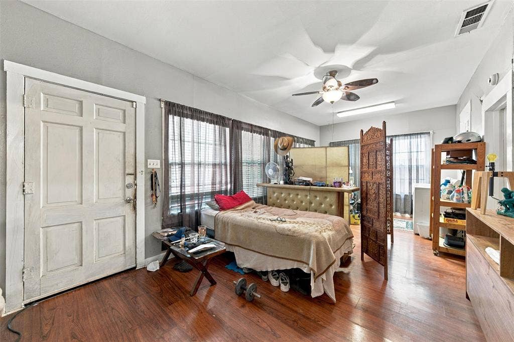 2725 Morrow Avenue, Waco, TX 76707 Spacious primary bedroom featuring hardwood flooring, ceiling fan with integrated lighting, French doors with sheer panel treatments, and abundant natural light from multiple windows