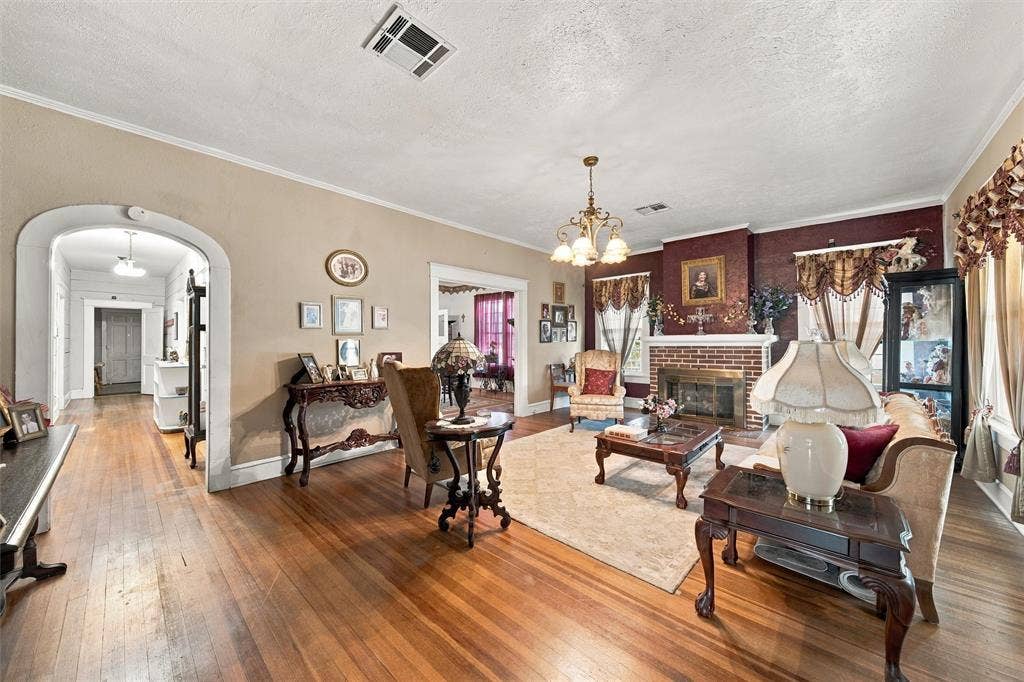 2725 Morrow Avenue, Waco, TX 76707 Hardwood flooring throughout, brick fireplace with mantel, arched entryway, and a chandelier