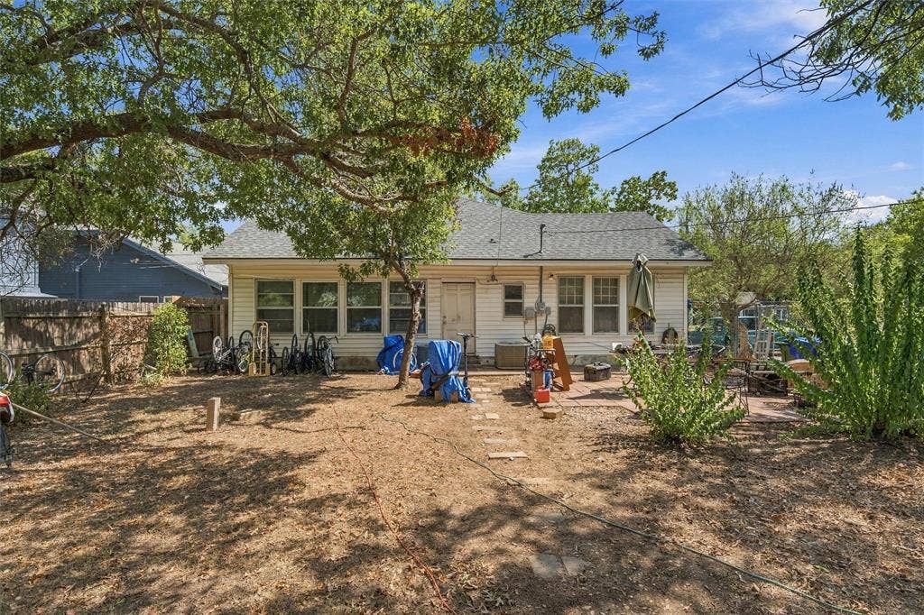2725 Morrow Avenue, Waco, TX 76707 Rear exterior with white siding and multiple windows, featuring a composition shingle roof and a paved patio area