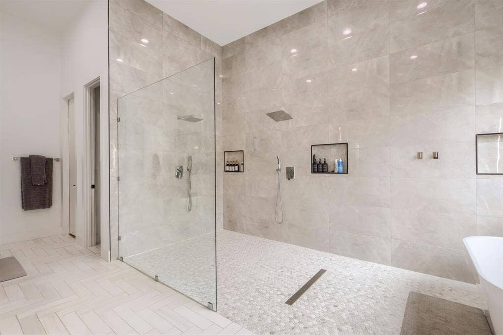 3950 Beechwood Lane, Dallas, TX 75220 Walk-in shower with full-height glass enclosure, rain showerhead, recessed wall niches, and pebble-tile flooring
