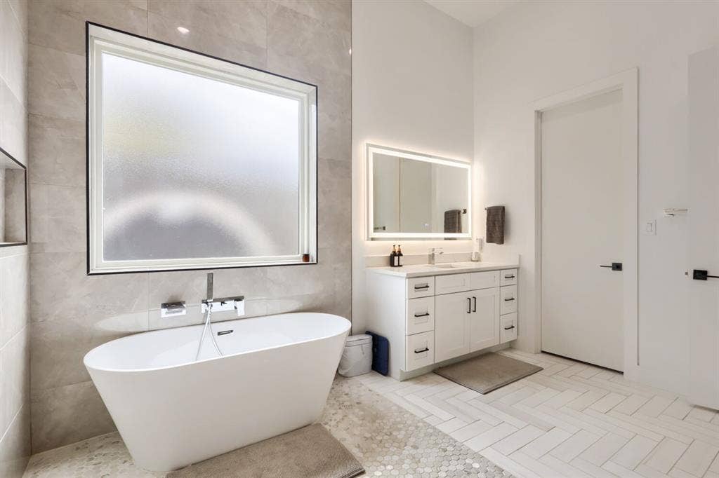3950 Beechwood Lane, Dallas, TX 75220 Freestanding soaking tub with a wall-mounted faucet, complemented by a large frosted window