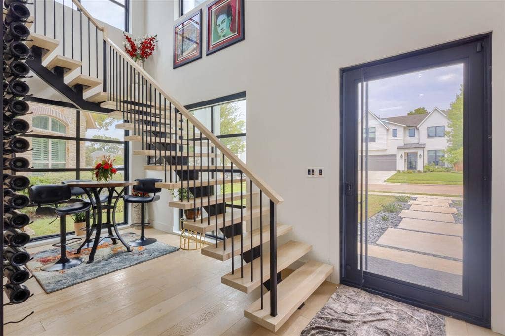 3950 Beechwood Lane, Dallas, TX 75220 Open-concept entry with wood-finish flooring, a floating staircase, and a floor-to-ceiling glass panel door