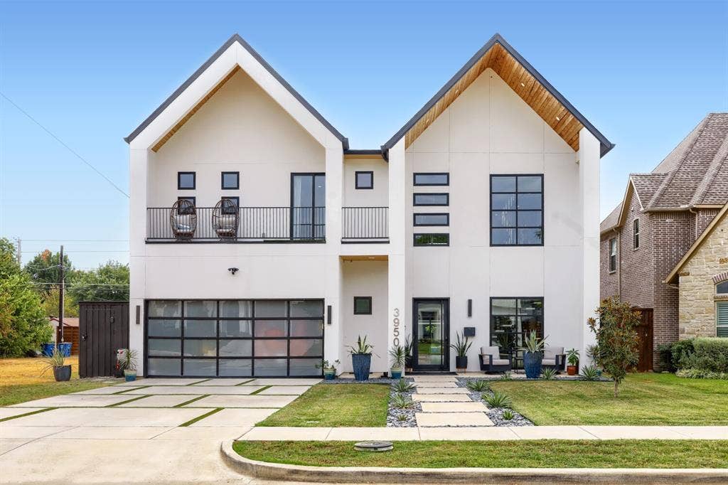 3950 Beechwood Lane, Dallas, TX 75220 Modern facade featuring two prominent gables with wood soffits, a glass-paneled garage door, and a second-story balcony with metal railings
