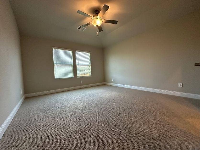 Vaulted ceiling with a ceiling fan, dual windows with blinds, neutral carpeting, and light-toned wall paint