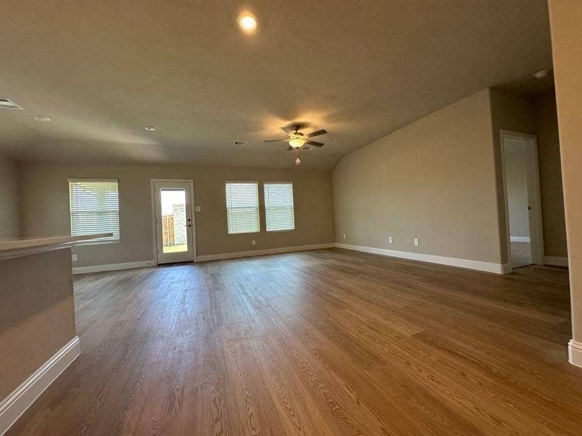 Spacious living area featuring wood-finish flooring, recessed lighting, and a ceiling fan