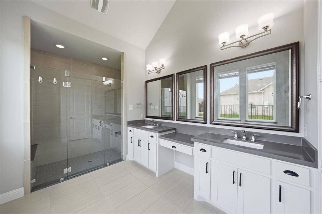 911 Midland Drive, Allen, TX 75013 Spacious bathroom featuring a large glass-enclosed shower, dual vanity with solid surface countertops, white cabinetry with dark hardware, and tiled flooring