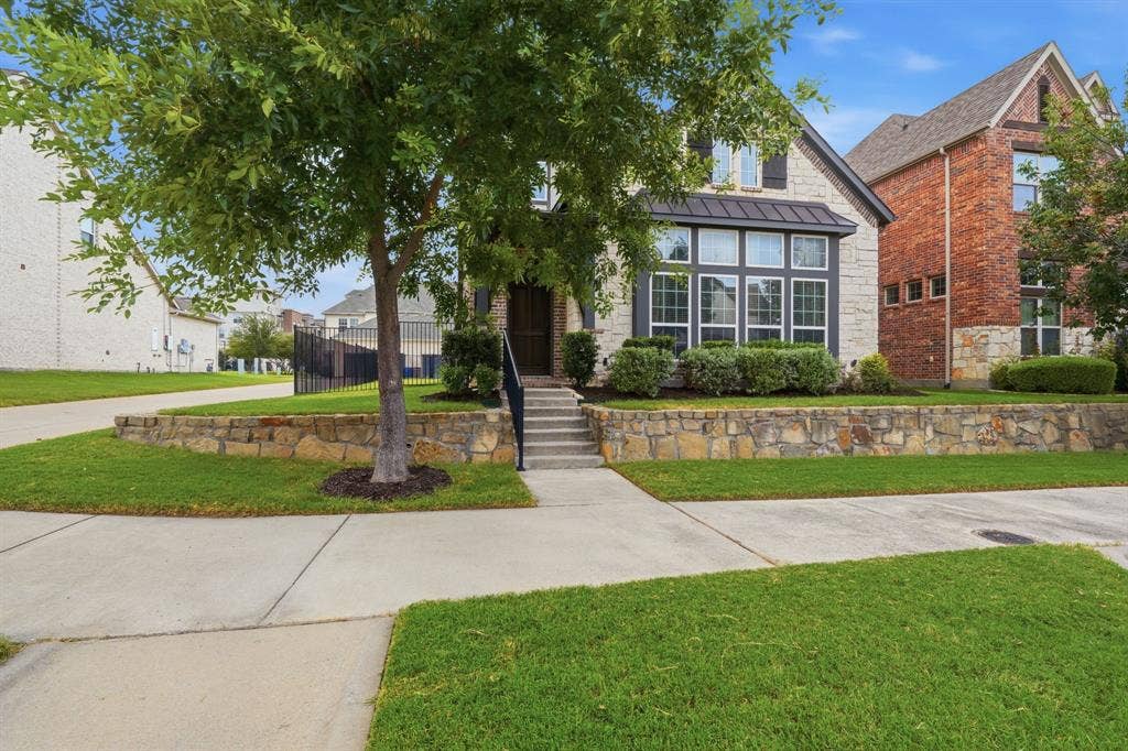 911 Midland Drive, Allen, TX 75013 Stone and brick facade with a bay window, a manicured lawn, and a stone retaining wall