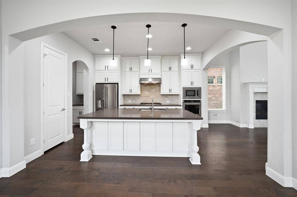 911 Midland Drive, Allen, TX 75013 Kitchen featuring an island with pendant lighting, stainless steel appliances, white cabinetry, and wood-finish flooring