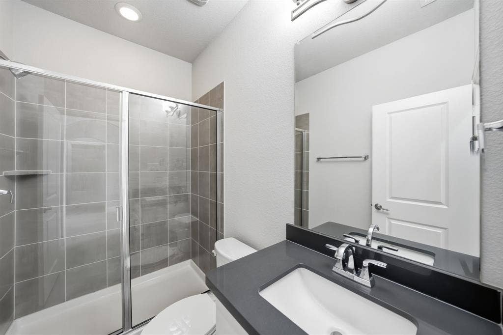 911 Midland Drive, Allen, TX 75013 Walk-in shower with gray tile surround and glass enclosure