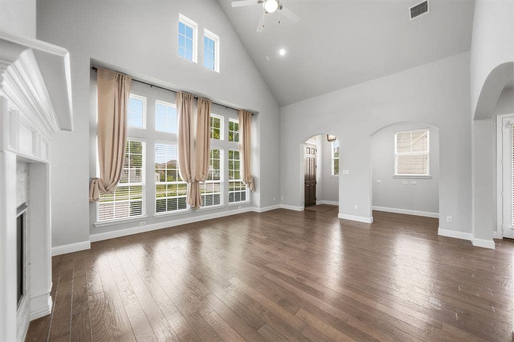 911 Midland Drive, Allen, TX 75013 Vaulted ceiling with a ceiling fan, wood-finish flooring, white fireplace mantel, and large picture windows