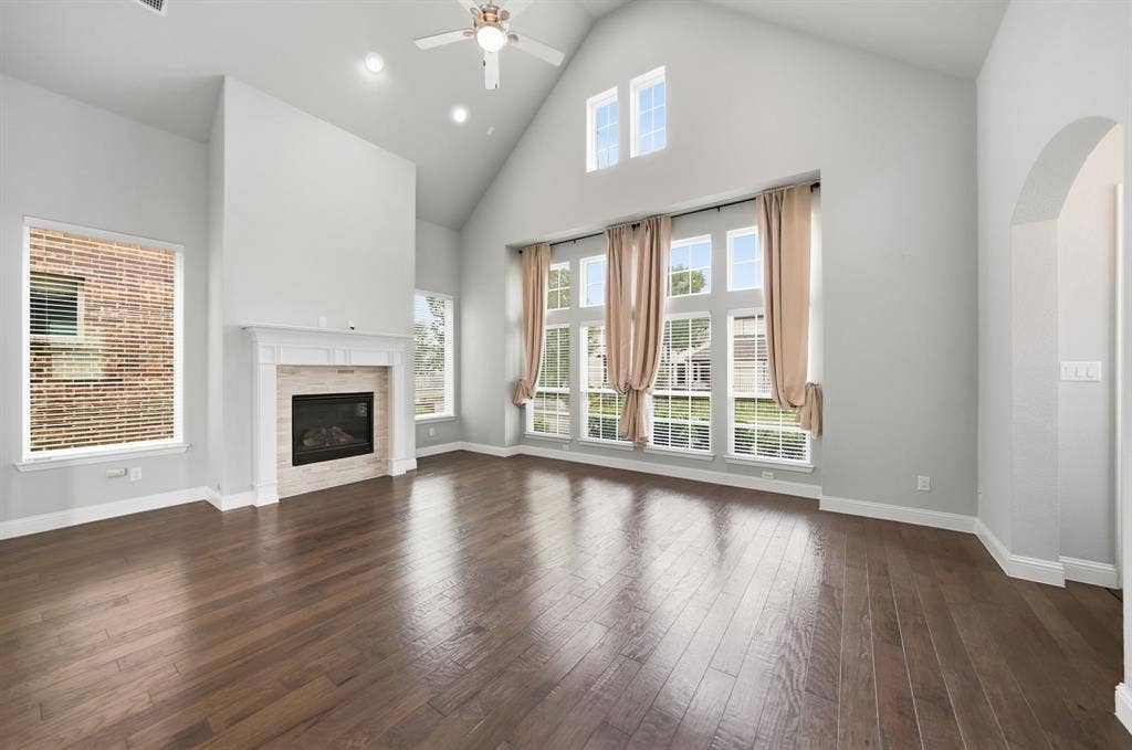 911 Midland Drive, Allen, TX 75013 Vaulted ceiling, wood-finish flooring, fireplace with stone surround, recessed lighting, and an arched entryway
