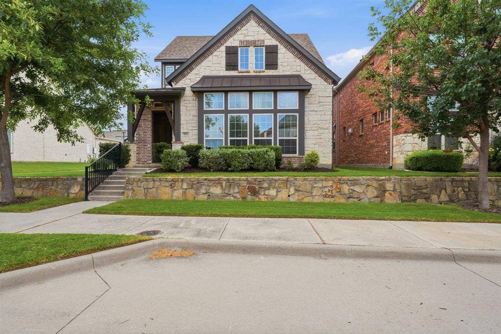 911 Midland Drive, Allen, TX 75013 Stone and brick exterior with dark trim and shutters, prominent bay window, covered entry, and tiered front landscaping