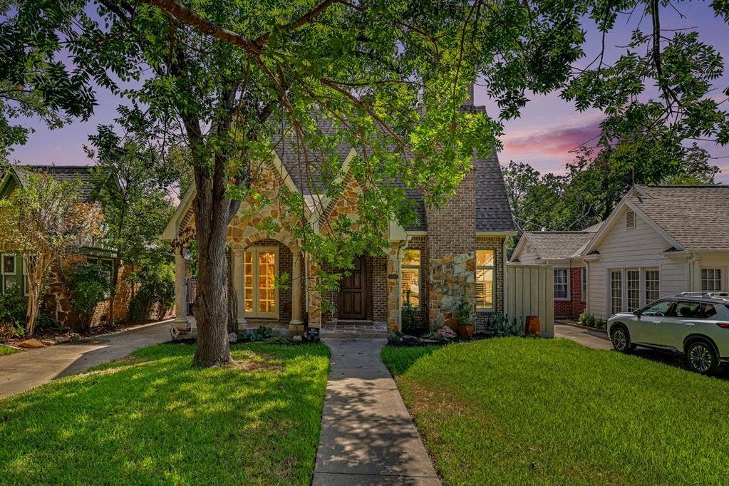 5542 Monticello Avenue, Dallas, TX 75206 Stone and brick facade, gabled roofline, arched entry, mature tree, and concrete pathway