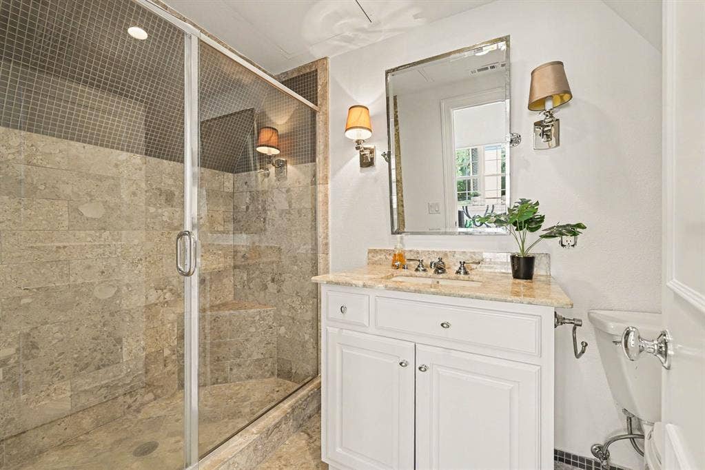 5542 Monticello Avenue, Dallas, TX 75206 Glass-enclosed shower with natural stone tile, an integrated shower bench, and a mosaic tile accent