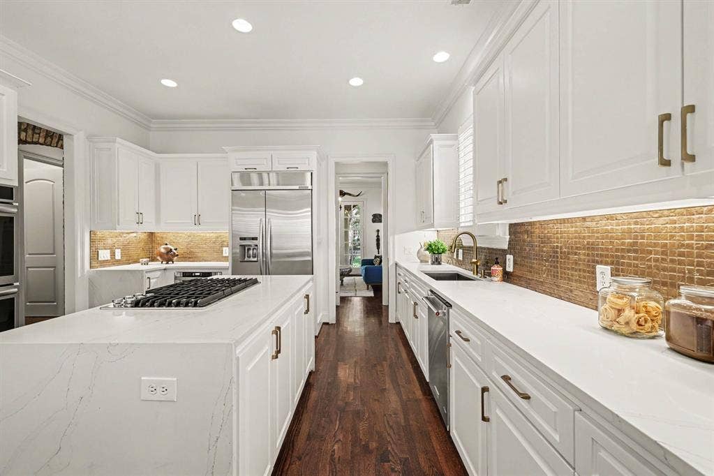 5542 Monticello Avenue, Dallas, TX 75206 Gourmet kitchen with white cabinetry, stainless steel appliances, a center island featuring a gas cooktop, and gold-toned tile backsplash