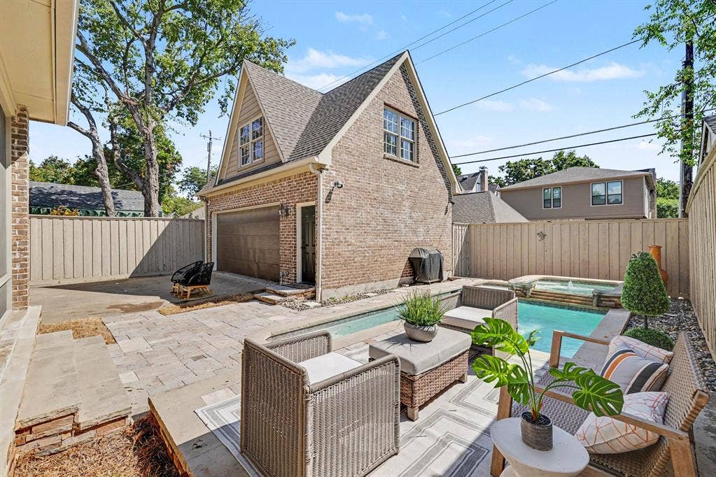 5542 Monticello Avenue, Dallas, TX 75206 Brick-clad detached garage with an upper dormer window, a built-in swimming pool, and a jetted spa