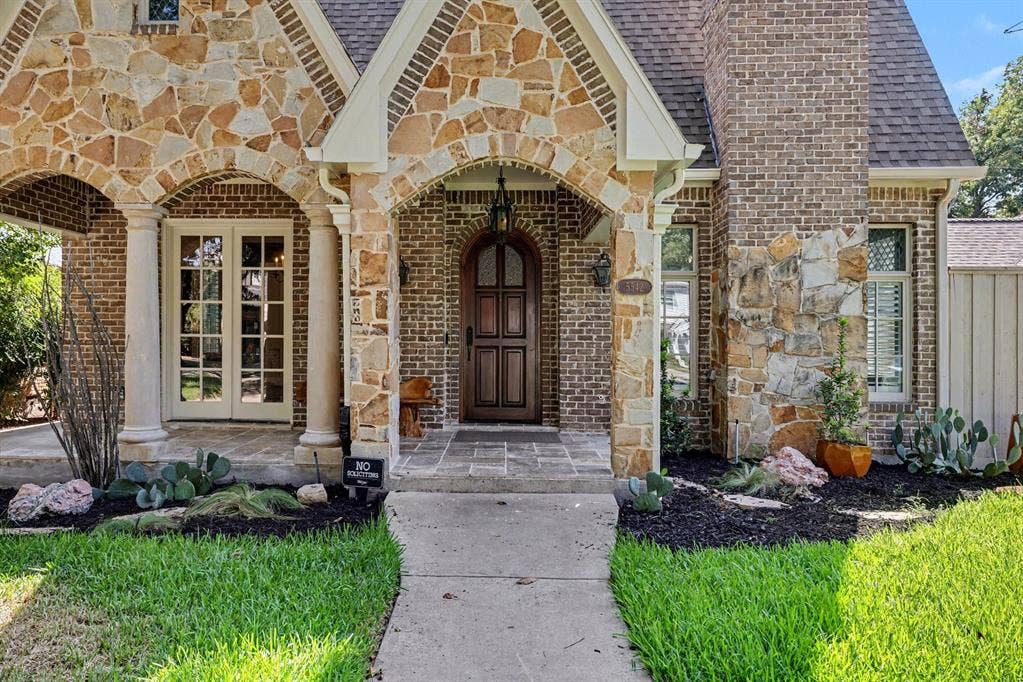5542 Monticello Avenue, Dallas, TX 75206 Stone and brick exterior with arched entryways, a solid wood front door, and a shingled roof