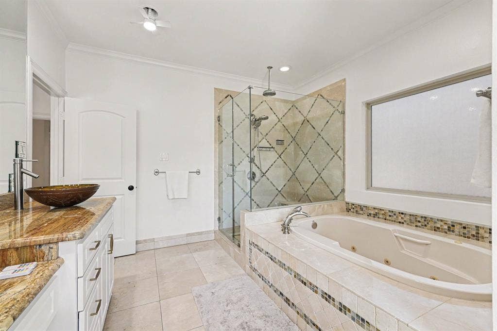 5542 Monticello Avenue, Dallas, TX 75206 Spacious bathroom featuring a glass-enclosed shower, a large soaking tub, a vanity with a vessel sink, and an expansive window