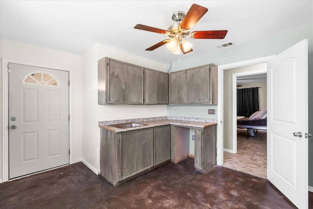 Kitchenette featuring gray wood-finish cabinetry, a single basin sink, and laminate countertops