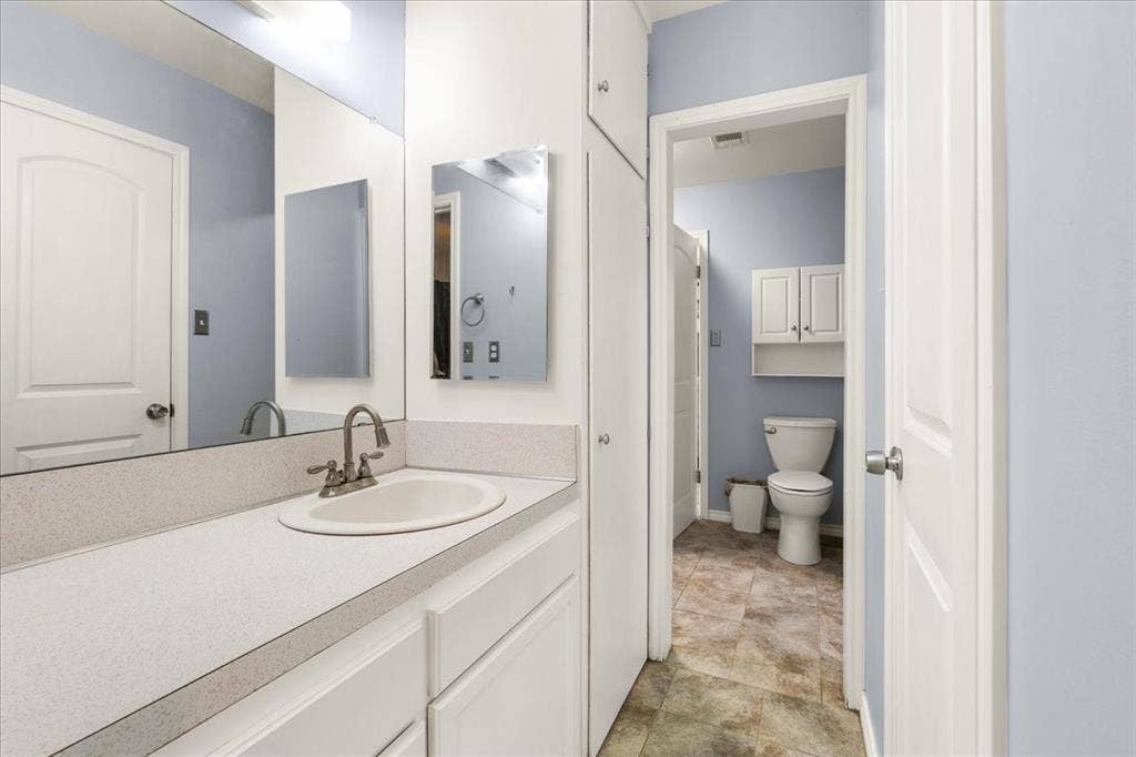 Vanity with integrated sink, dual-handle faucet, and white cabinetry