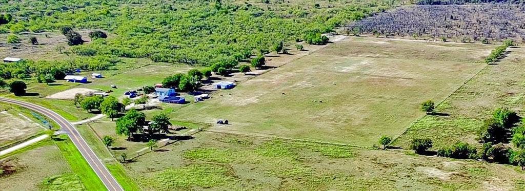 Expansive land parcel featuring cleared areas, natural foliage, and a paved road