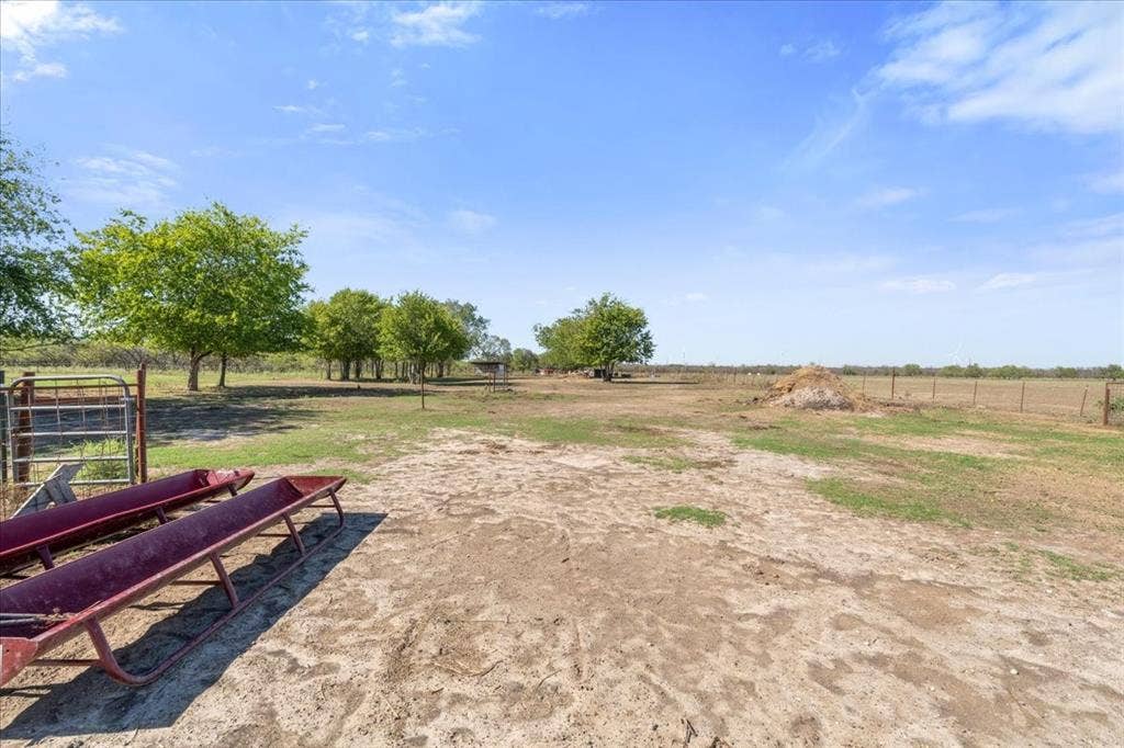 Expansive outdoor area featuring mature trees and a perimeter fence