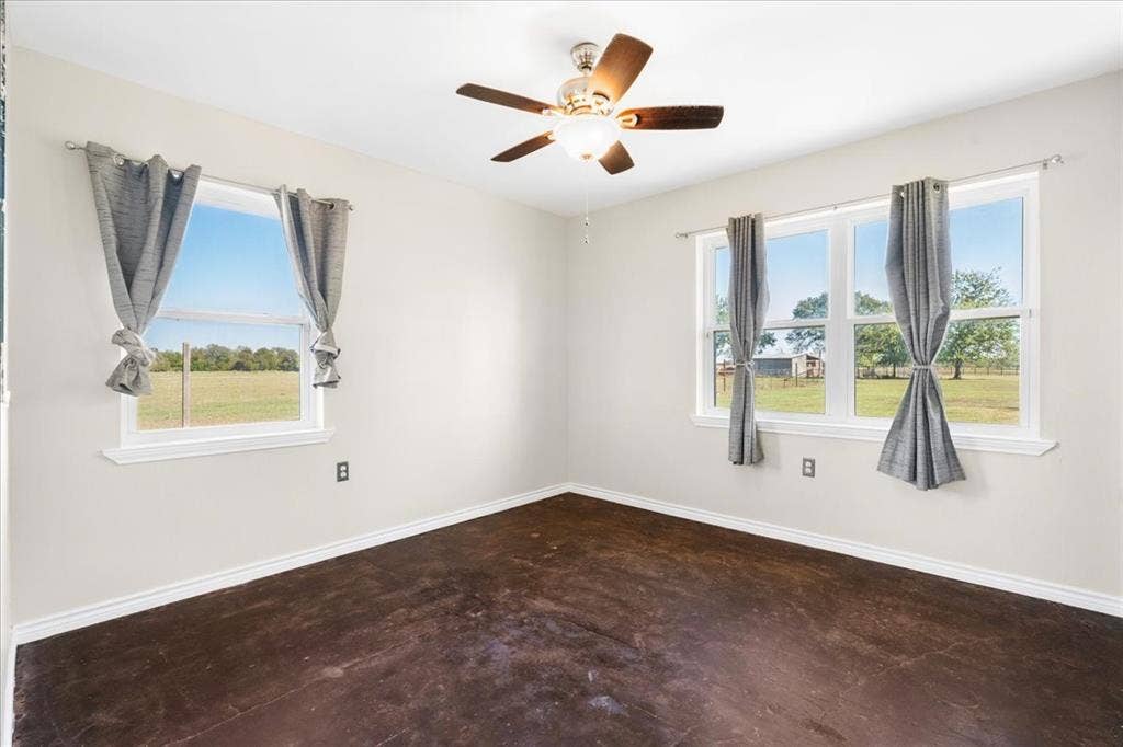 Wood-finish flooring with white trim, light-colored walls, and a ceiling fan with integrated lighting
