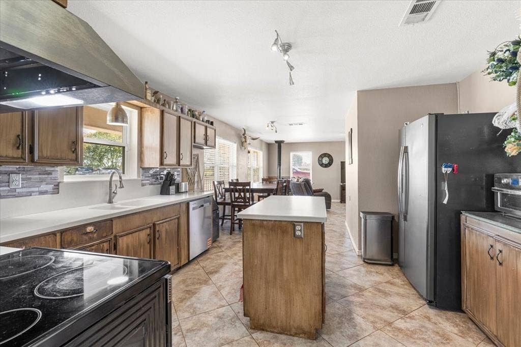 Kitchen featuring wood cabinetry, a center island, and tile flooring