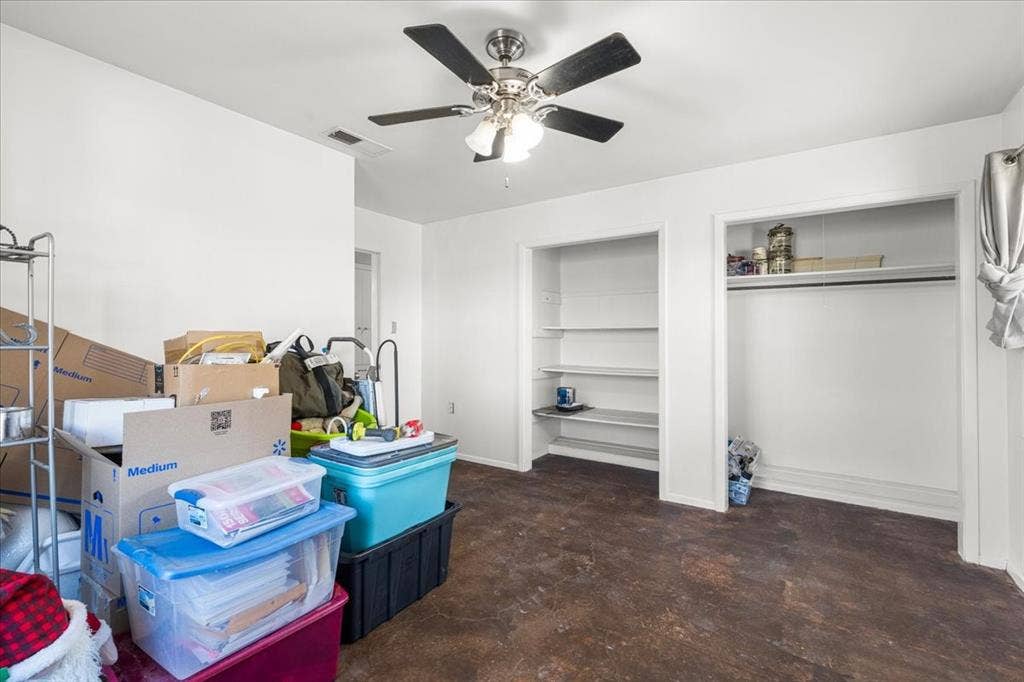 Ceiling fan light fixture, wood-finish flooring, built-in shelving, white walls, and a recessed air vent