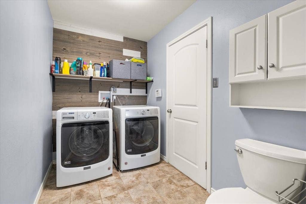 Laundry area featuring wood-finish wall paneling, open shelving, and neutral tile flooring