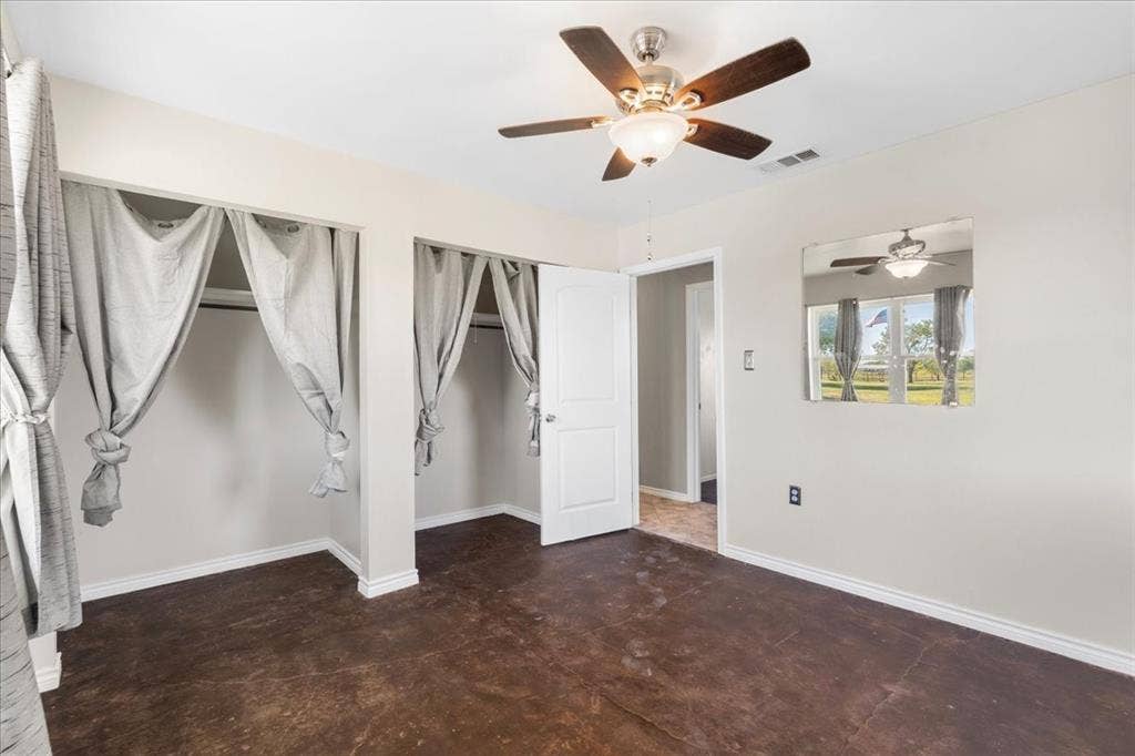 Smooth concrete flooring, ceiling fan with integrated lighting, window, and white trim