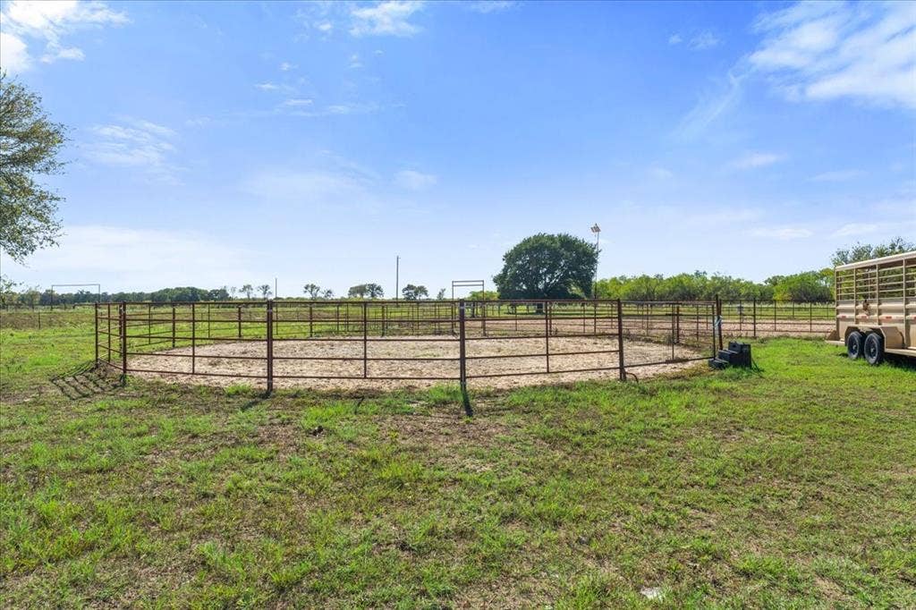 Circular metal fence enclosure on a grass and dirt lot