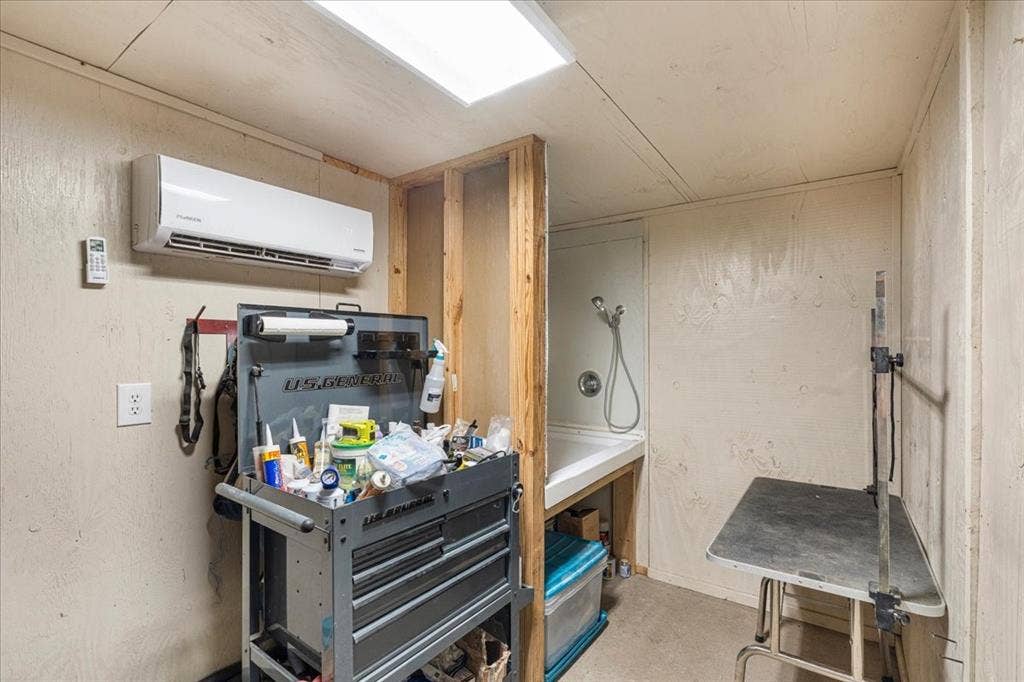 Wall-mounted mini-split system, recessed overhead lighting, and built-in utility sink with shower attachment