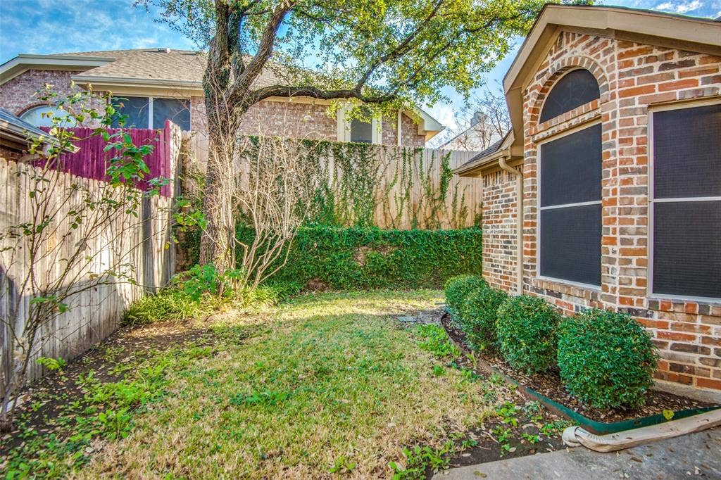 1913 Piney Creek Boulevard, Denton, TX 76205 Brick exterior with an arched window, featuring a manicured shrub bed and a grassy yard