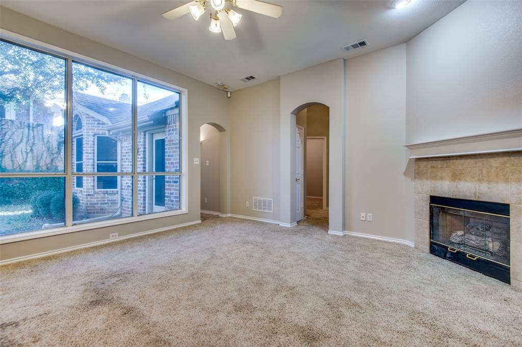 1913 Piney Creek Boulevard, Denton, TX 76205 Expansive windows, arched doorways, ceiling fan, and a fireplace with a stone surround
