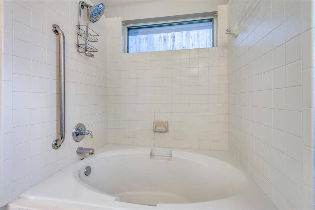 1913 Piney Creek Boulevard, Denton, TX 76205 Built-in soaking tub with chrome fixtures, white subway tile surround, and an integrated grab bar