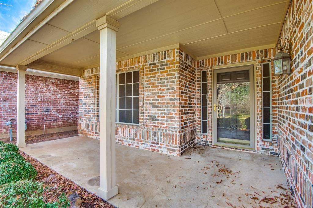 1913 Piney Creek Boulevard, Denton, TX 76205 Covered front entry featuring a brick facade, decorative columns, and a porch light