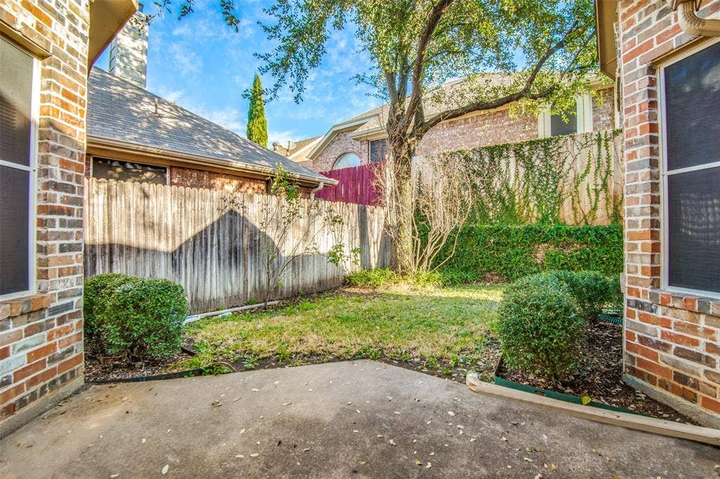1913 Piney Creek Boulevard, Denton, TX 76205 Private outdoor patio with a concrete surface, bordered by brick exterior walls and a wooden fence