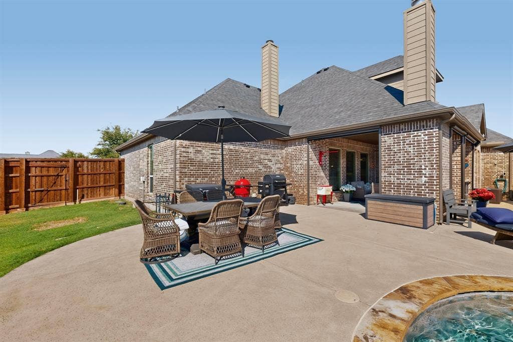 5020 Lindy Court, Midlothian, TX 76065 Brick exterior with multiple chimneys, covered patio, concrete patio, and fenced yard