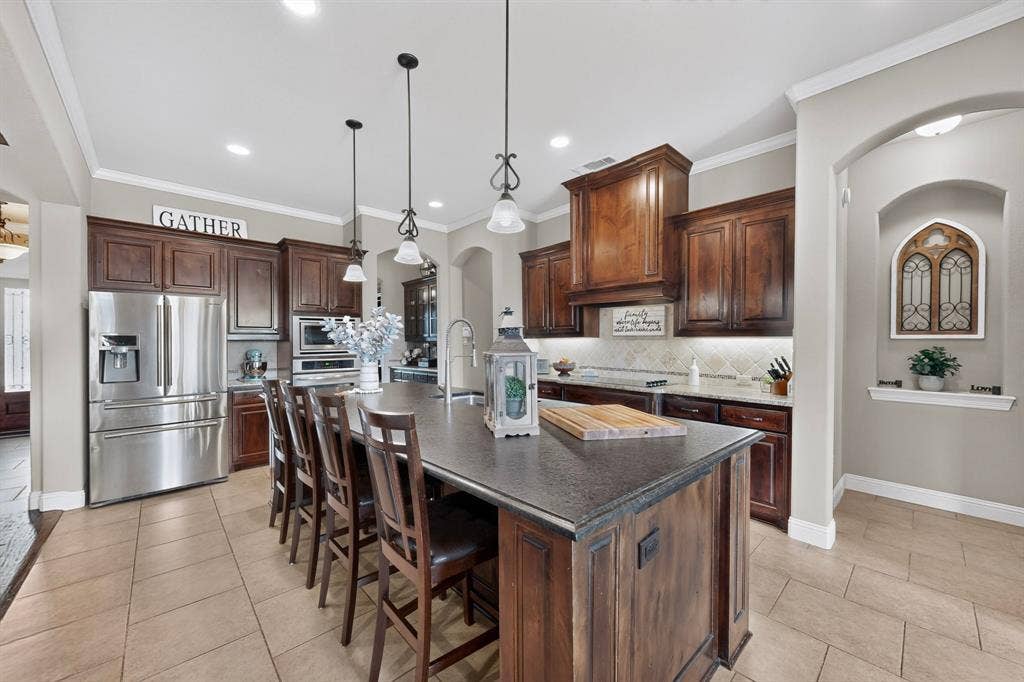 5020 Lindy Court, Midlothian, TX 76065 Spacious kitchen with a large island, wood-finish cabinetry, stainless steel appliances, and tiled flooring