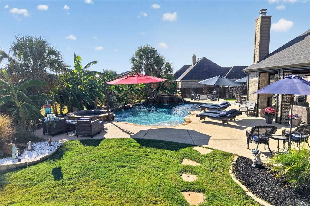 5020 Lindy Court, Midlothian, TX 76065 Landscaped backyard featuring a freeform swimming pool with a rock waterfall and integrated spa