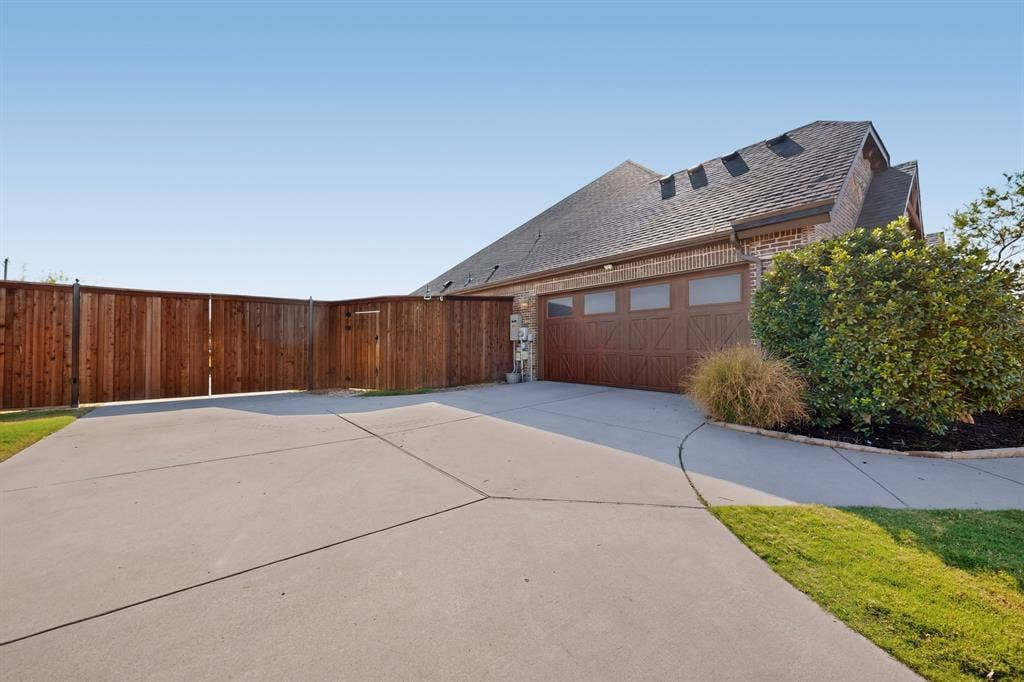 5020 Lindy Court, Midlothian, TX 76065 Concrete driveway with an integrated walkway, leading to a multi-car garage with a wood-finish door and frosted windows
