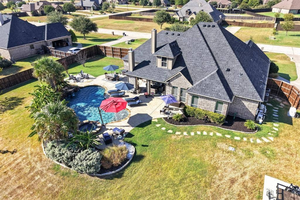5020 Lindy Court, Midlothian, TX 76065 Brick exterior residence with a multi-level roofline, featuring an in-ground swimming pool, an integrated spa, and a stone patio