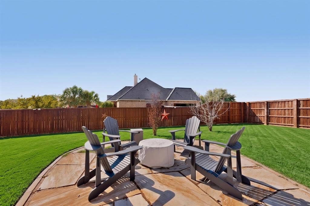 5020 Lindy Court, Midlothian, TX 76065 Expansive backyard featuring a stone patio, manicured lawn, and privacy fencing