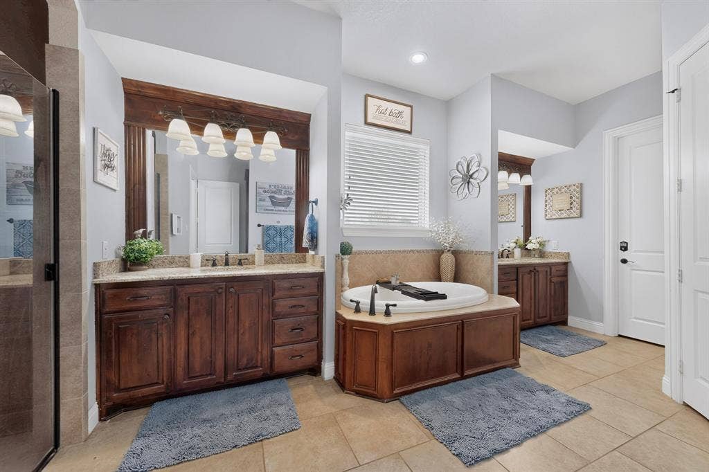 5020 Lindy Court, Midlothian, TX 76065 Dual wood-finish vanities with stone countertops, a built-in soaking tub, and a separate glass-enclosed shower