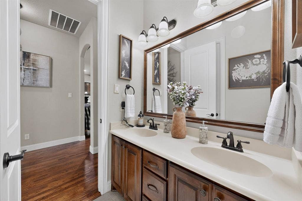 5020 Lindy Court, Midlothian, TX 76065 Double vanity with integrated sinks, dark wood-finish cabinetry, and a large framed mirror with overhead lighting