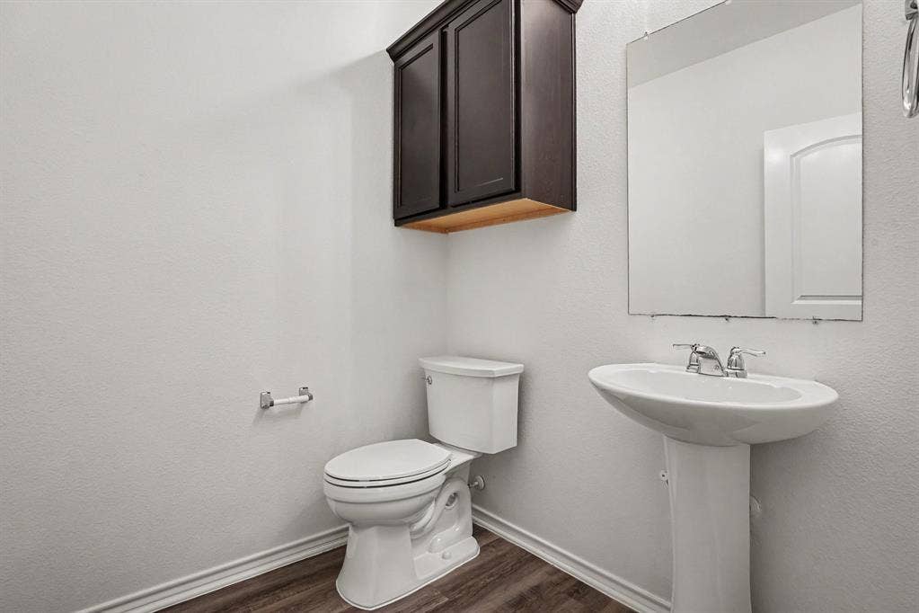 257 Michelle Drive, Grand Prairie, TX 75051 A convenient half bath with a pedestal sink and wall-mounted storage.
